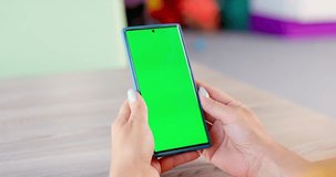 Back view of young woman holding smartphone with green screen and looking on it