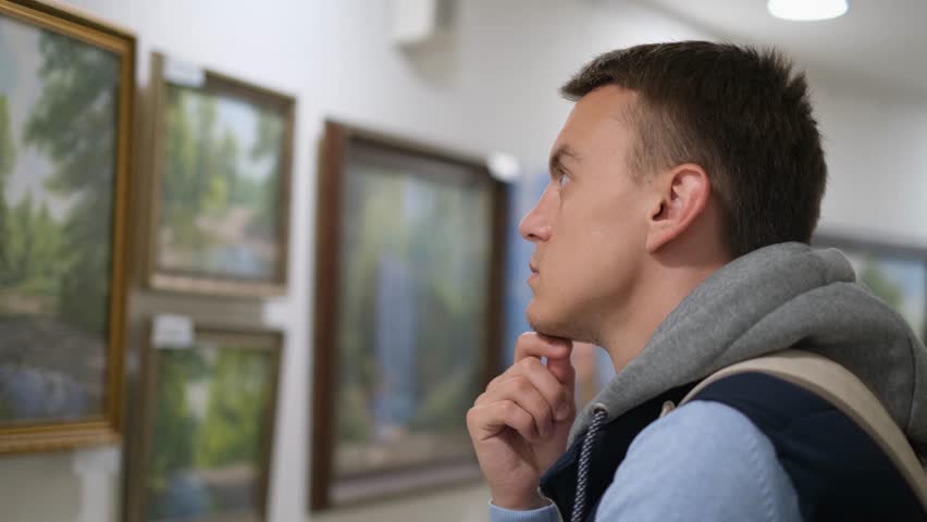 Young man looking at paintings in an art gallery Royalty-Free Stock Footage #1110630931