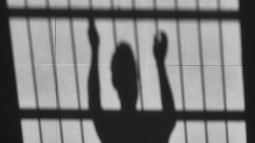 Angry furious prisoner in prison hitting jail door with hand,cast shadow on the floor,upset slave in captivity punches the bars silhouette | Shutterstock HD Video #1110636411