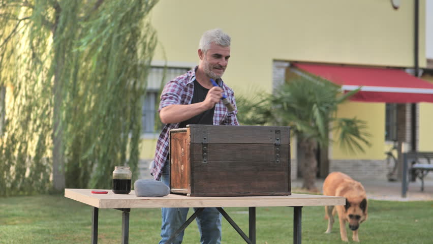 Hobby carefree mature man restores old furniture in the home garden,caucasian male enjoying time varnishing painting antique cabinet in the backyard slow motion | Shutterstock HD Video #1110636425