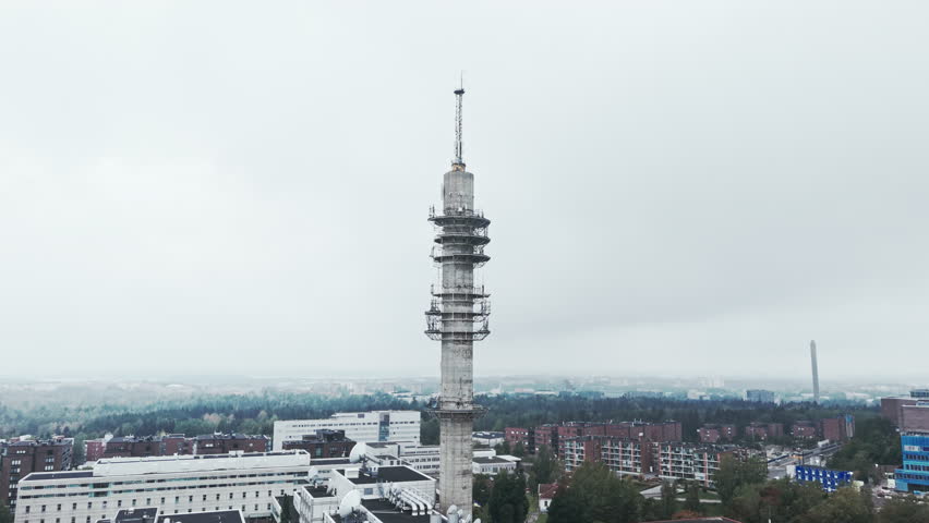 Aerial shot of a bleak industrial concrete television and radio link tower in Pasila, Helsinki, Finland on a bright and foggy day. Camera approaching.