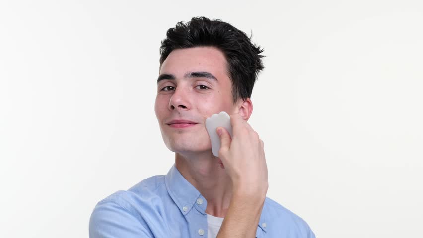 Smiling Man Using Gua Sha Tool for Facial Massage