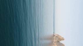 Aerial panoramic view of beautiful sunset above sea. Beautiful seascape. Sun glare, small waves on the water surface. Evening. Horizon. Nobody. No people. Never-ending beauty of nature. Vertical video