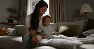 Mom and child looking book in sun ray. Cinematic Chinese, Japanese, Korean, Asian. Incredible heartwarming bond between mother and son. Relaxed happy millennial mother and baby spending time together