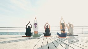 Professional athletes meditate against sea at sunset. International group enjoys taking care of health and internal world together - Powered by Shutterstock - Get 15% off with code: PIKWIZARD15