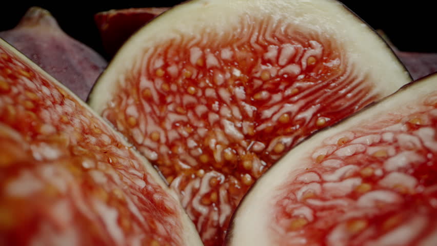 The Camera Moves Across Sliced Halves of Red Figs on a Black Background. Dolly slider extreme close-up. Royalty-Free Stock Footage #1110649755