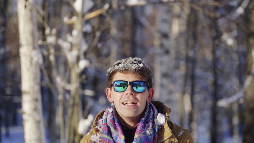 Happy young caucasian man portrait in sunglasses throwing snow up laugh. Handsome guy enjoy winter merry Christmas New Year vacation having fun smiling. Leisure activity, holiday concept. Slow motion