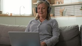 Smiling mature Caucasian woman grandmother businesswoman freelancer typing on laptop at home listening music on headphones communicate on social network concept modern technology and elderly people - Powered by Shutterstock - Get 15% off with code: PIKWIZARD15