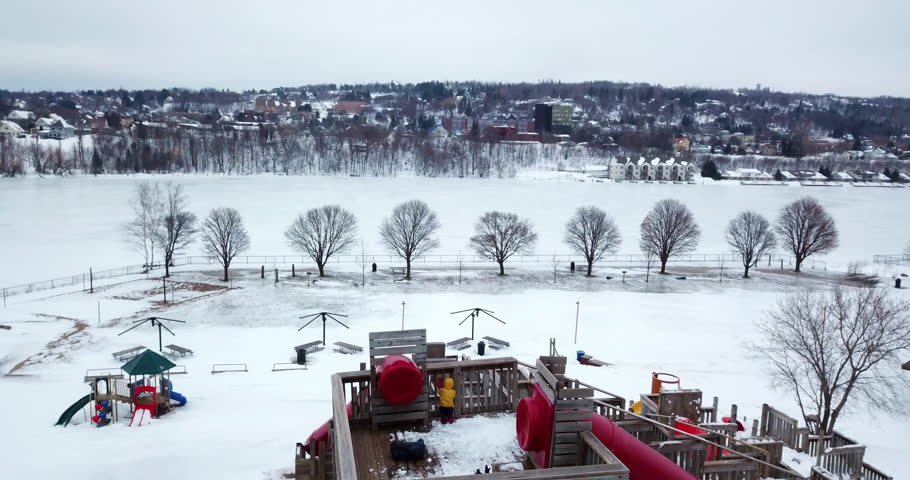 Aerial Backward Shot Of Park Near Frozen Portage Lake Against Sky During Winter - Houghton, Michigan