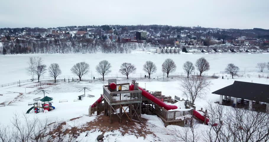 Aerial Panning Shot Of Park Near Frozen Portage Lake Against Sky During Winter - Houghton, Michigan