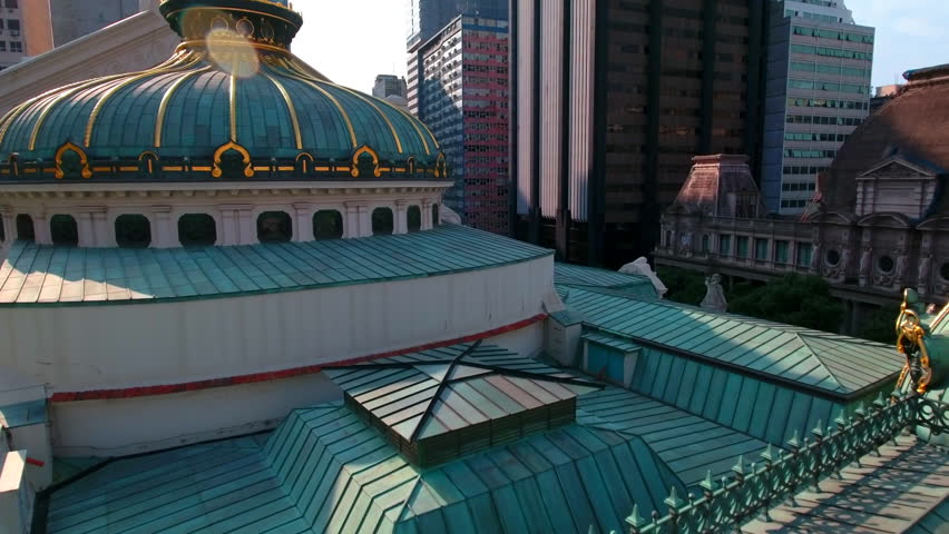 Aerial Backward Shot Of Theatro Municipal With A Flag Amidst Buildings In City - Rio de Janeiro, Brazil