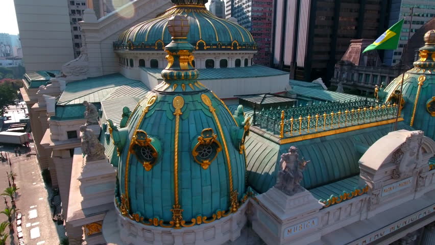 Aerial Panning Shot Of Theatro Municipal With Flag Amidst Buildings In City - Rio de Janeiro, Brazil