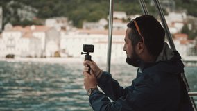 Young man taking video 
of Establishing view of Perast old town on Kotor bay, Montenegro