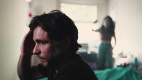 Stressed boyfriend listening to screaming girlfriend arguing with him in background. couple fighting in bedroom. Male person sitting by bedside suffering from a bad relationship - Powered by Shutterstock - Get 15% off with code: PIKWIZARD15