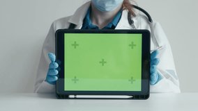 Doctor demonstrates green screen tablet with advertisement for medical services, providing patients with quick access to information personal virtual office, online medical record in clinic. Chromakey