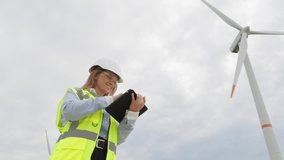 A female scientist with a digital tablet studies the possibilities of wind energy and makes a significant contribution to renewable energy. Technological progress: a female designer in a signal vest - Powered by Shutterstock - Get 15% off with code: PIKWIZARD15
