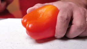 man's hand cuts a red sweet pepper with a knife on a board close-up. slicing red sweet pepper. cutting vegetables - Powered by Shutterstock - Get 15% off with code: PIKWIZARD15