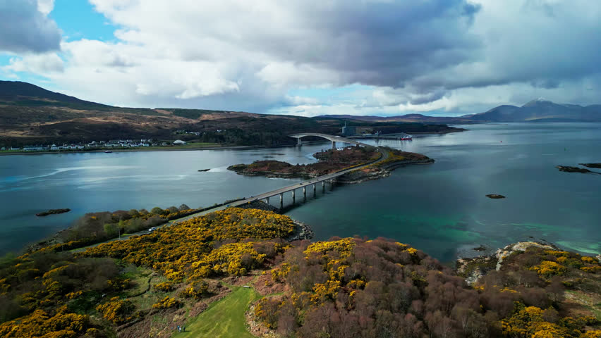 Panoramic overview of yellow coastal hillsides leading to the Skye Bridge in Scotland on a cloudy day