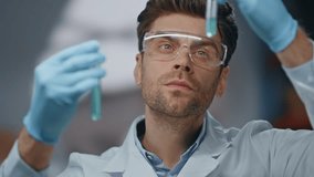 Smart researcher exploring medicines in innovation laboratory close up. Serious scientist in glasses looking at test tubes with preparation. Focused lab specialist working on new vaccine from disease. - Powered by Shutterstock - Get 15% off with code: PIKWIZARD15