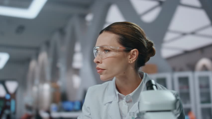 Biotechnological researcher typing computer developing medical vaccine in laboratory close up. Serious woman scientist holding test tube with drug. Skilled female biotechnologist working in lab pc.
