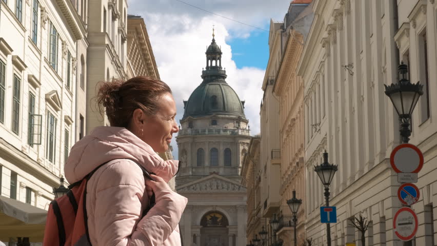 Woman at st. stephens basilica. A smiling woman tourist with backpack pass her free time in the street against St. Stephen