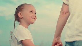 Happy kid in park with mom. Kid holding his mothers hand against blue sky. Mom, daughter are walking through park, Weekend. Holiday family. Mom holds her kid girl by hand in park. Happy family concept - Powered by Shutterstock - Get 15% off with code: PIKWIZARD15