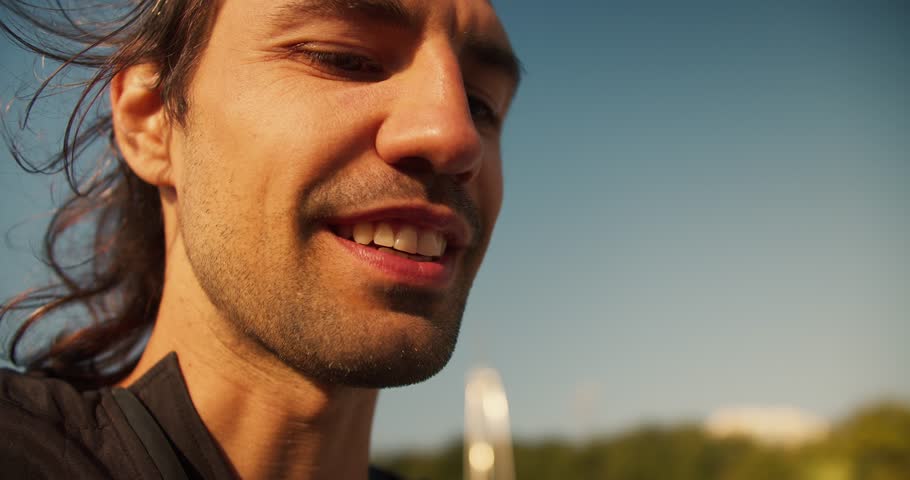 Close-up shot of the face of a happy brunette guy with stubble who eats a hot dog. A cheerful guy eats a hot dog and smiles during his day off Royalty-Free Stock Footage #1110693199