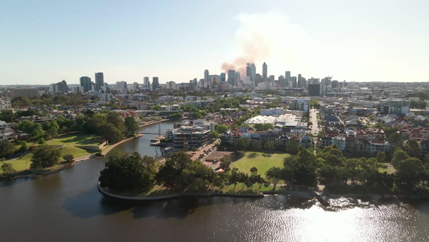 Tracking aerial shot of Perth CBD with smoke in the background from a fire. Captured 24th October 2023. Royalty-Free Stock Footage #1110695025