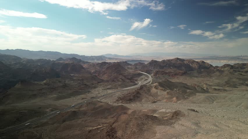 Aerial descending above Mojave Desert and Lake Mead Recreation Area in Nevada with view of bridge above Hoover Dam