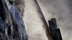 Stream of hot mineral water from a geothermal natural spring in slow motion. Falling drops and splashes of warm water with hydrogen sulfide on calcium and phosphorus deposits. Vertical video