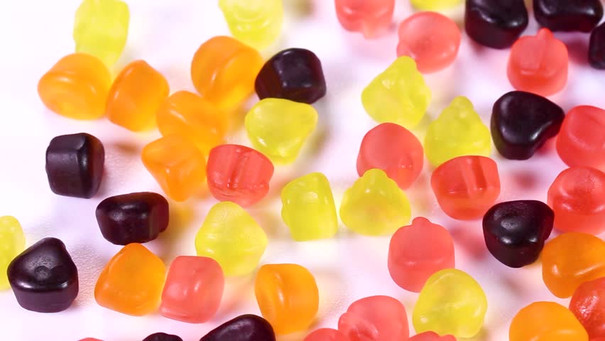Fruit gummies on white background rotating