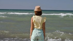 Impressed young woman waving hands and looking at the sea waves. 4k video footage UHD 3840x2160