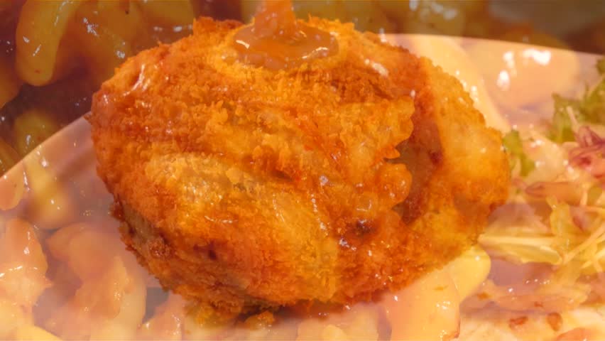 Sprinkling sweet and sour sauce on crispy round fried pork cutlet