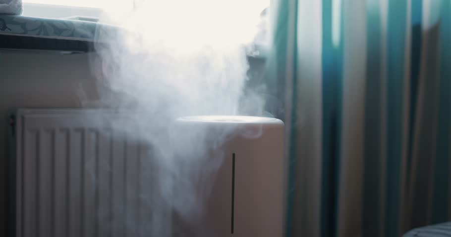 Steam comes out of an air humidifier, a man's hand plays with water mist Royalty-Free Stock Footage #1110703755
