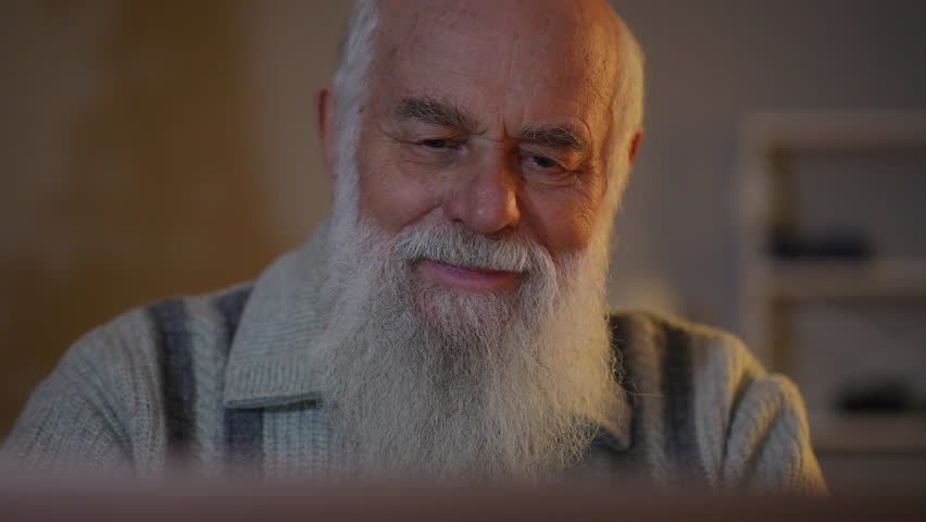 Close-up: an elderly bearded man with positive emotions on his face