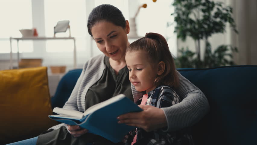Happy mother reading a book with her cute little daughter, family relationship Royalty-Free Stock Footage #1110705187