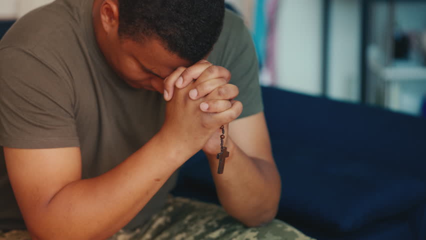 Pensive soldier praying, sitting in room alone, holding wooden cross in hands Royalty-Free Stock Footage #1110705287