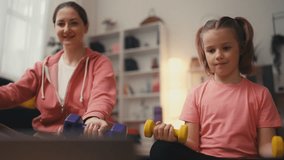 Mom and child watching online tutorial and lifting dumbbells together, fitness