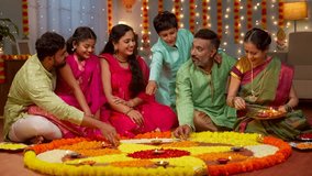 Group of Indian family members decorating Flower rangoli using Diya lamps at home for diwali celebration - concept of holiday gathering, traditional custom and rituals. - Powered by Shutterstock - Get 15% off with code: PIKWIZARD15