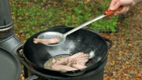 Kitchener preparing pork ribs on hot cast iron pan outdoors. 4k video footage