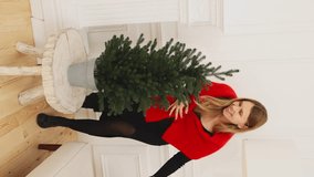girl laughs and hugs a small green artificial Christmas tree on a white background. new year christmas. vertical video