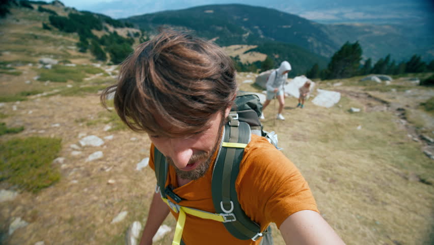 Man on mountain path with his family, wife and kids. Travel blogger hiking with backpack on mountain filming himself selfie vlog. YouTuber on journey adventure Royalty-Free Stock Footage #1110717001