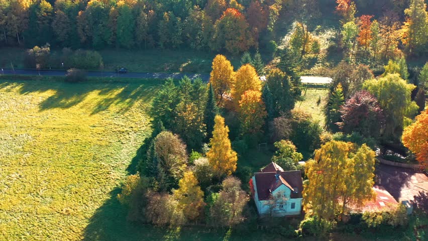 Aerial View of a Romantic Residential House on a Lawn Surrounded by Autumn-Colored Trees