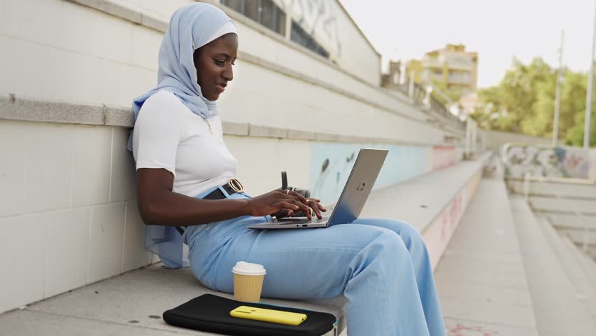 Young Inspired African Student Girl wearing muslim hijab working on laptop - Cultural Diversity 