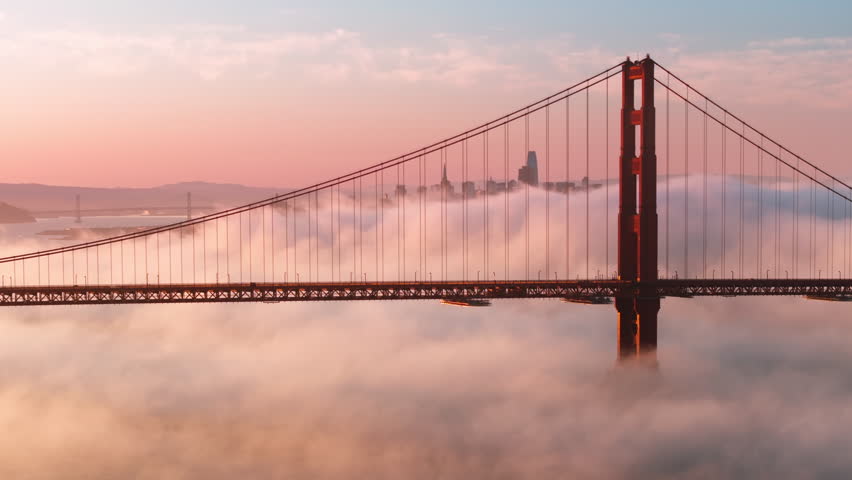 Breathtaking views on major USA landmark. Tourism background. Epic landscape with cinematic pink clouds floating around scenic red Golden Gate bridge with San Francisco cityscape on motion background