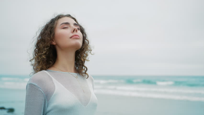 Side profile view girl enjoy moment of peace, mental relaxation, no stress. Calm young woman taking deep breath of fresh air meditating with eyes closed standing outdoors at ocean waves on background Royalty-Free Stock Footage #1110727741