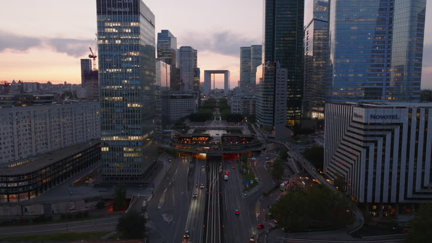 Busy multilane road and tunnel under modern urban district at sunset. High rise office buildings in popular La Defense borough. Paris, France Royalty-Free Stock Footage #1110728557
