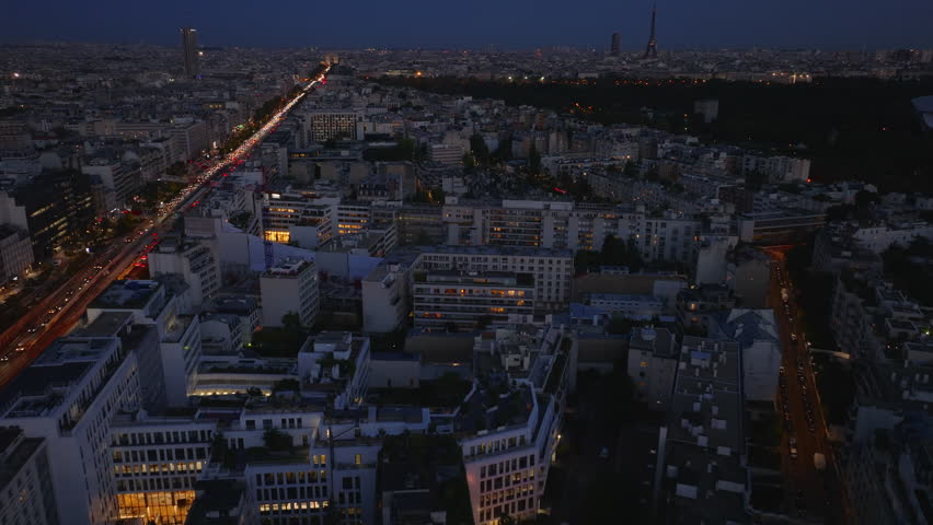 Forwards fly above buildings in urban borough at night. Busy multilane wide boulevard Avenue Charles de Gaulle and Eiffel Tower in distance. Paris, France Royalty-Free Stock Footage #1110728585
