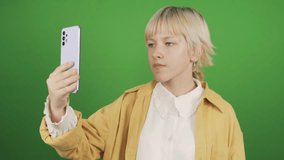 Teenage girl talking via smartphone via video call. Close-up. Isolated on a green background, chromakey.