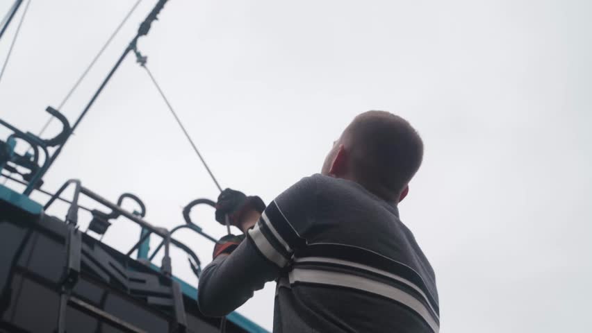 Bottom view of professional driver stands at back side of trolleybus and pulls cable rope to move trolley pole and start vehicle.